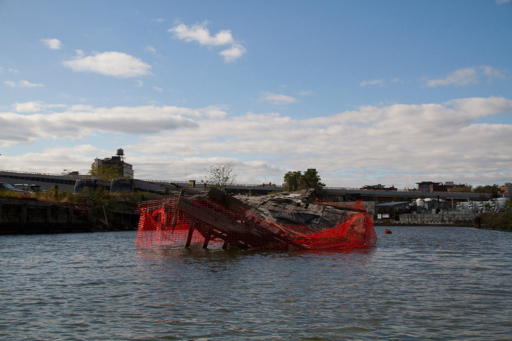 Vista más cercana del muelle hundido en el Canal Gowanus con la malla naranja de alerta.