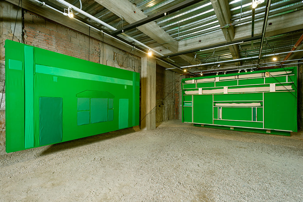 Third floor of Again's intallation showing large scale facades made with green screen and other green fabrics