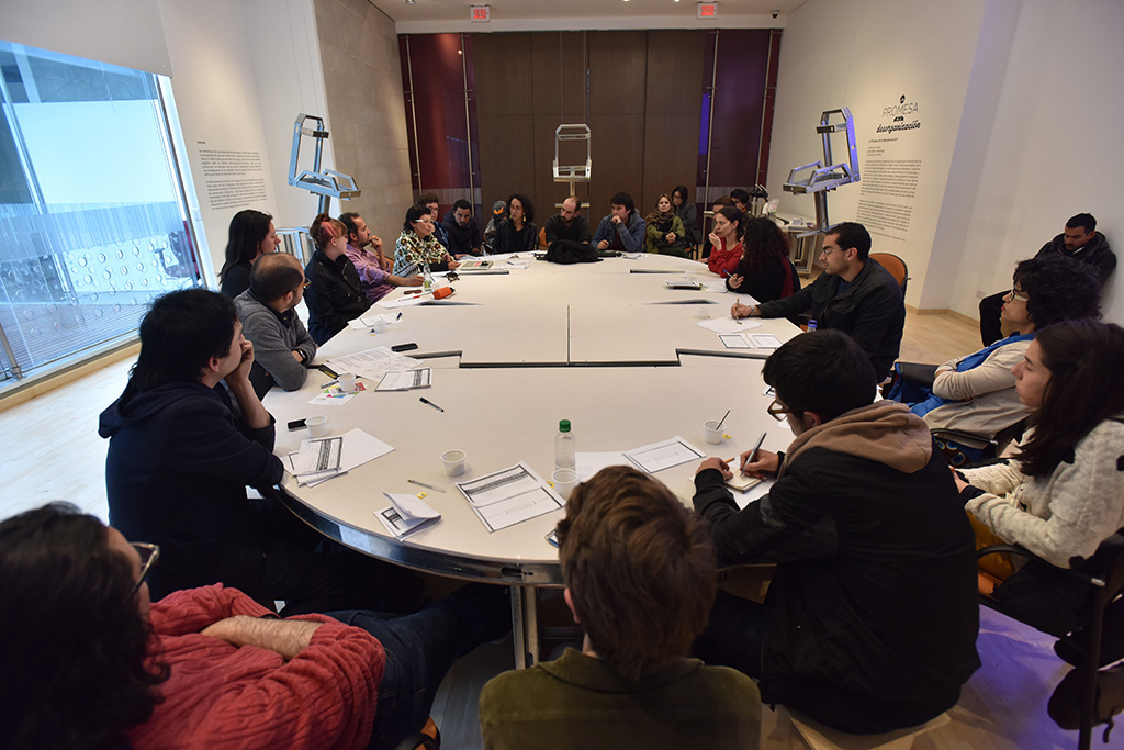 People sitting at the table made for the exhibition The Promise of Disorganization