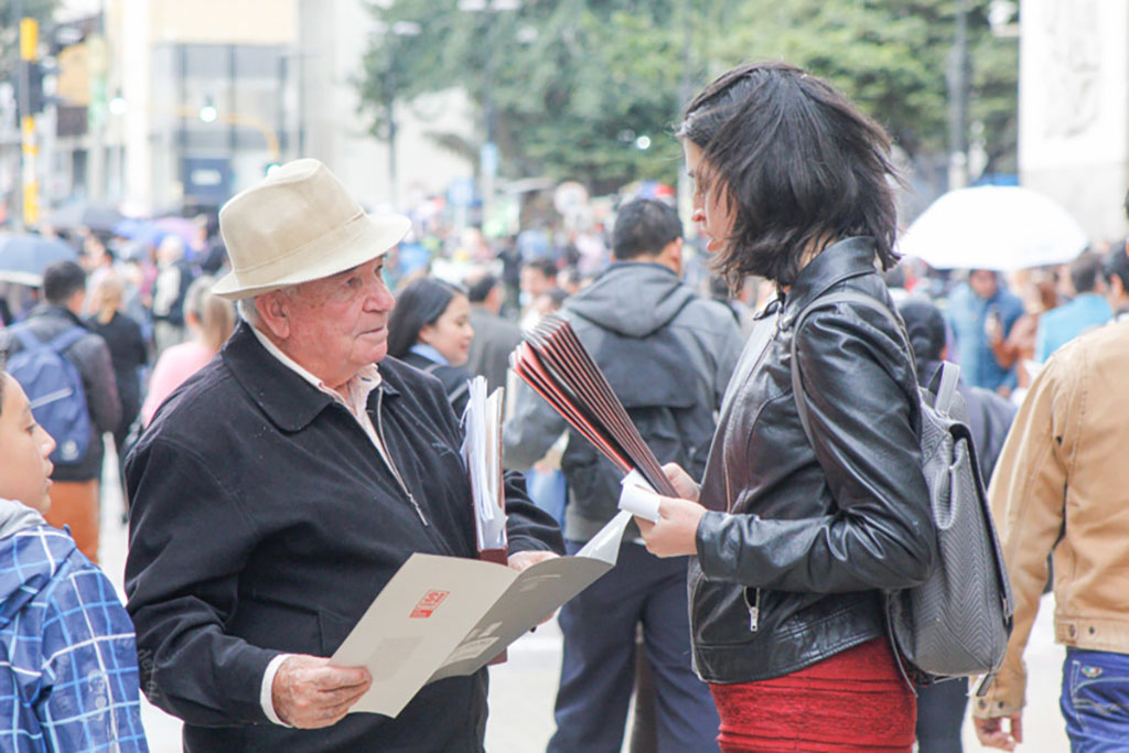 La gente conversa sobre el folleto impreso de la Subasta Santafé y Sicorp.